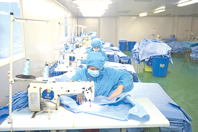 广西柳州圣美康医疗器械有限公司职工加班加点，赶制疫情一线医用手术衣。（图片由广西柳州市委组织部提供）